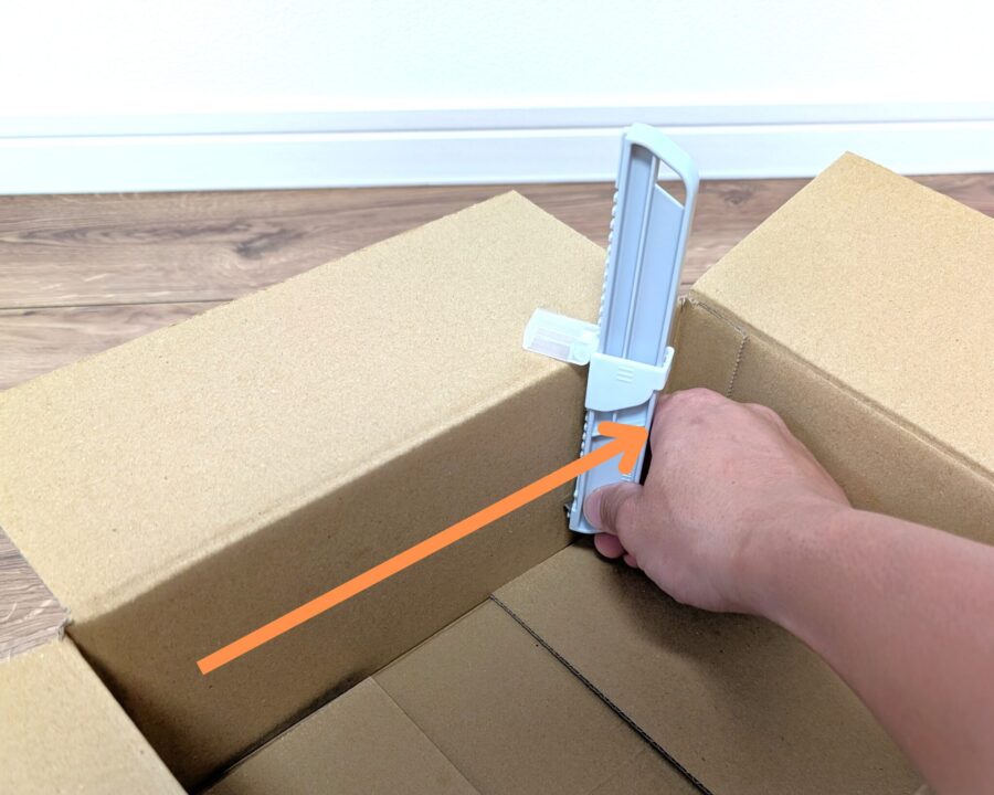 ダンボールサイズ調整カッターを使っているところの写真。スライドして罫書く様子。