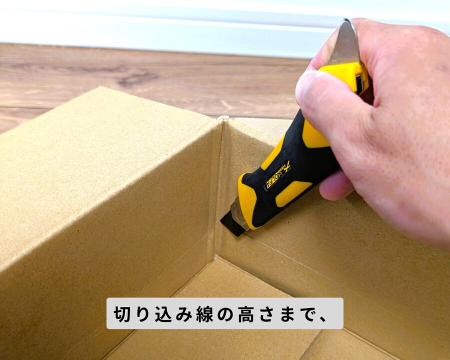 ダンボール箱の四隅をカッターで切るところの写真。