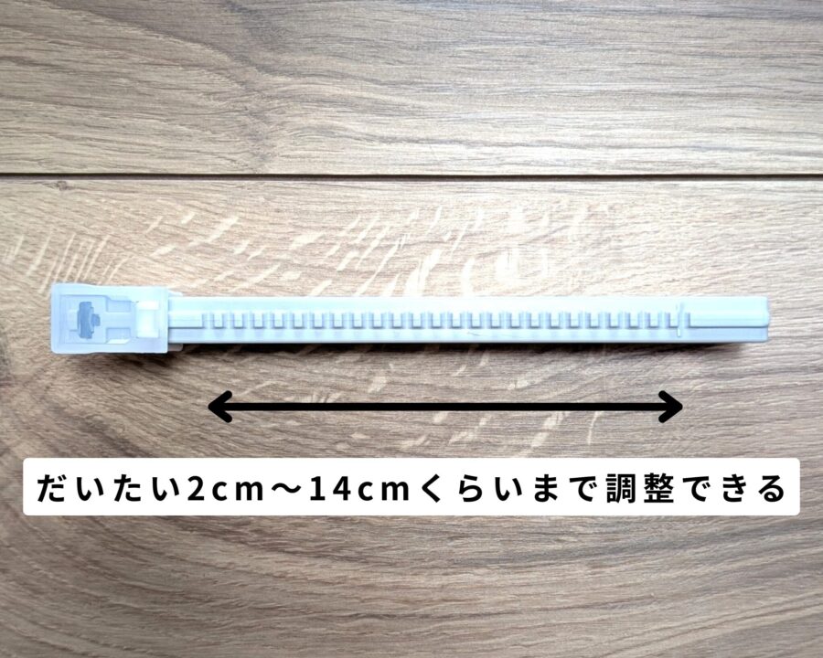 フローリングにダンボールサイズ調整カッターが立てて置いてある。上から見た写真。矢印で調整幅を示して「だいたい2cmから14cmくらいまで調整できる」と記載。