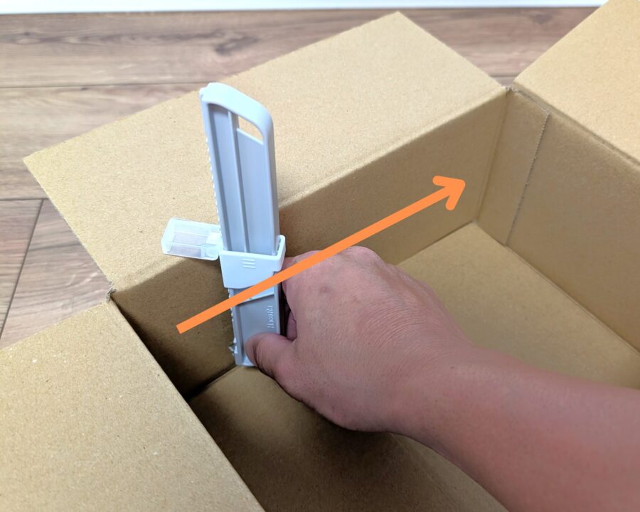ダンボールサイズ調整カッターを使っているところの写真。スライドして罫書く様子。