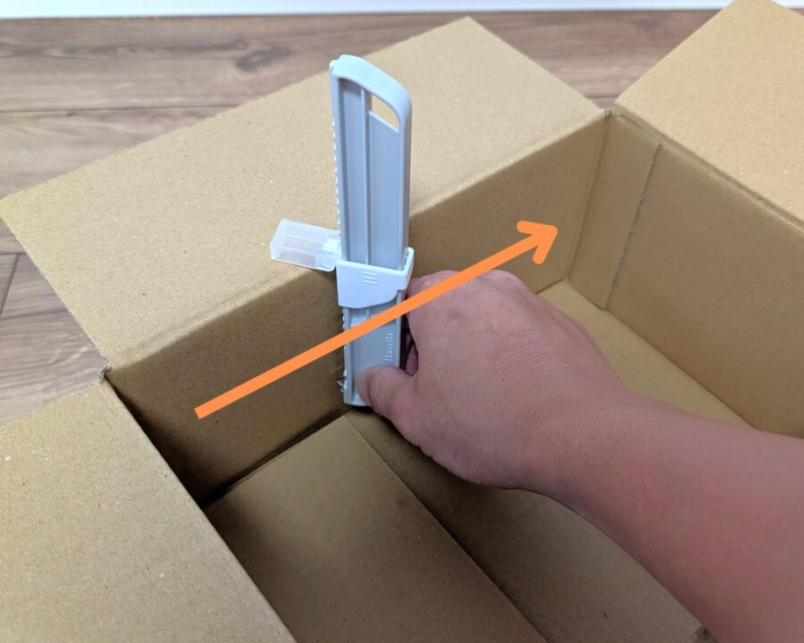 ダンボールサイズ調整カッターを使っているところの写真。スライドして罫書く様子。