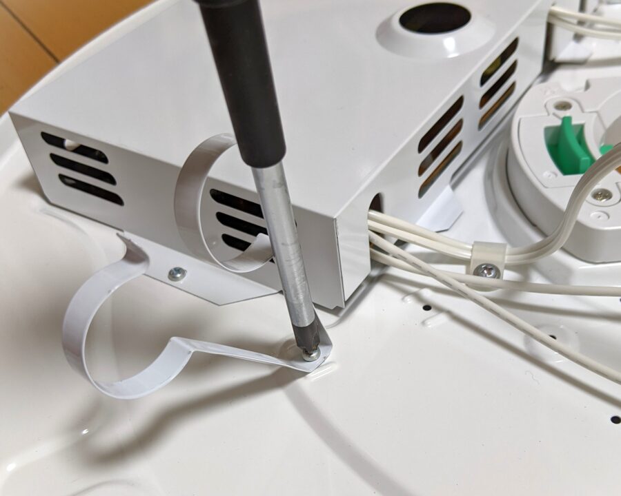 蛍光管を付けるホルダーのネジをドライバーで外している様子。