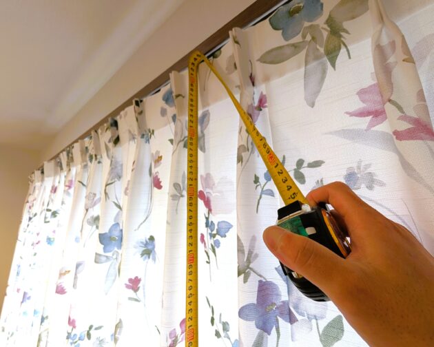 コンベックスを使ってカーテンの高さを測っているところの写真。