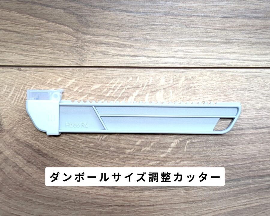 フローリングにダンボールサイズ調整カッターが置いてある。側面を写した写真。