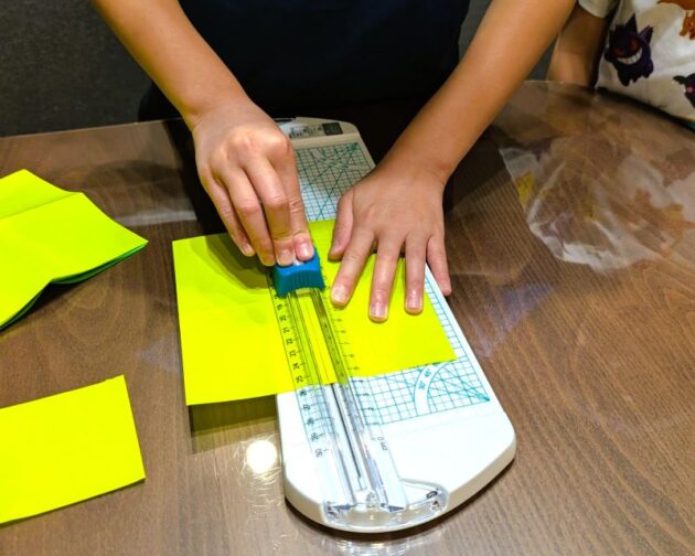 子どもがスライドカッターでおりがみを切っている